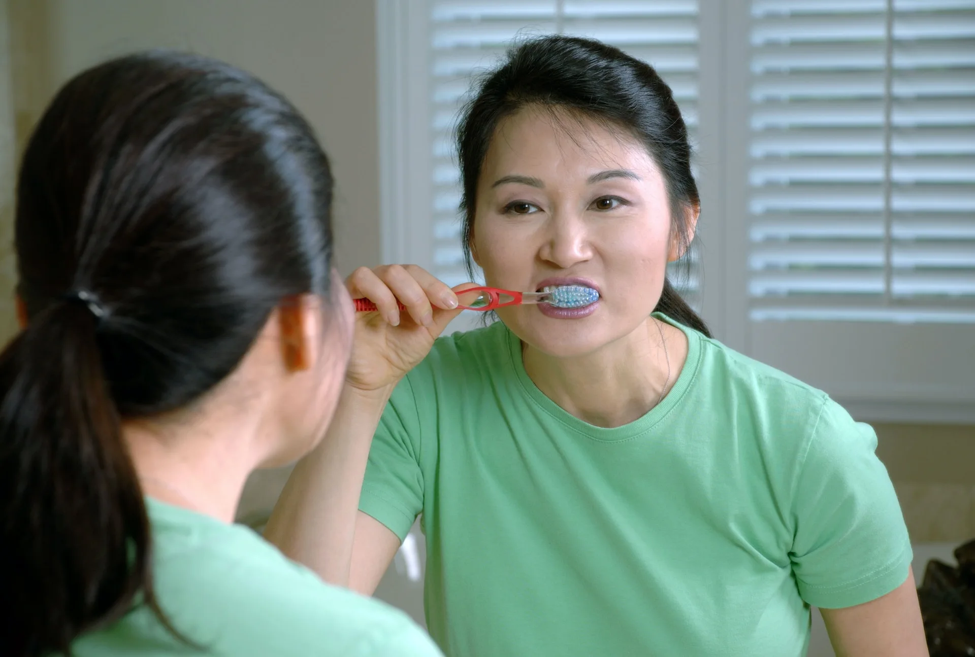 Mujer cepillándose los dientes y cuidando su higiene oral